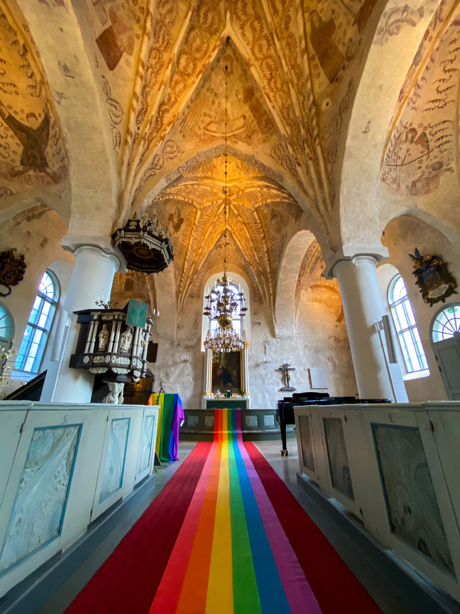 sjundeå kyrkas mittkorridor klätt i regnbågsfärger ledande upp till altaren