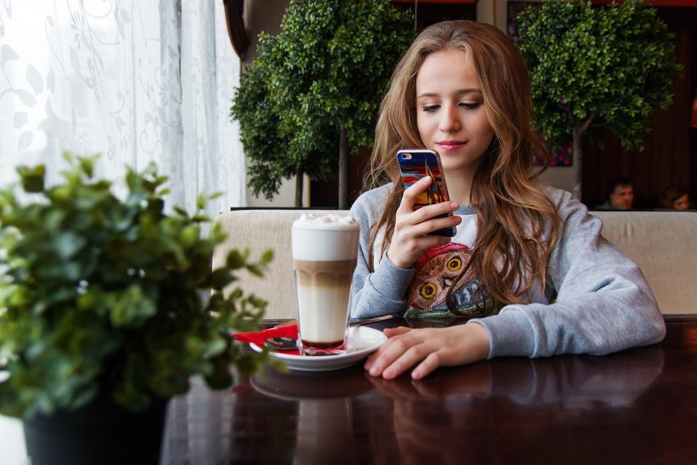 Flickan med mobilen i en kafé
