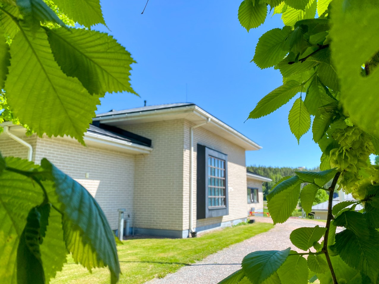 Sjundeå församlingshem på sommaren och lövträd.